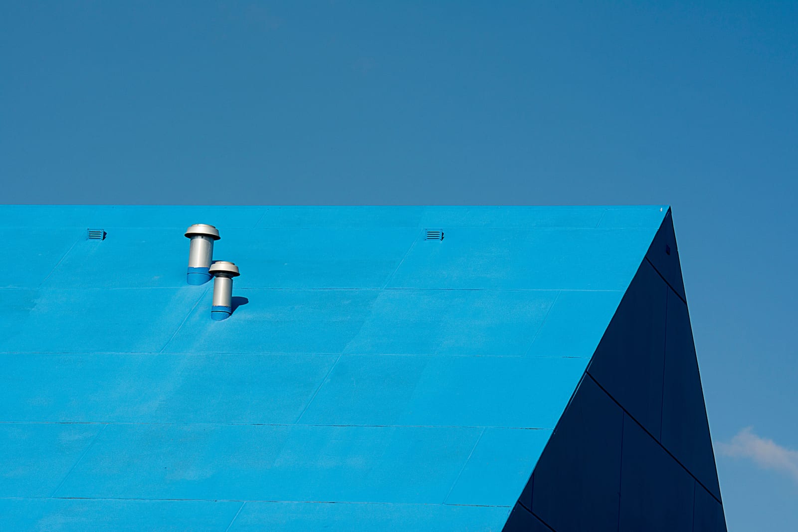 Blue pitched metal roof with two ventilation penetrations